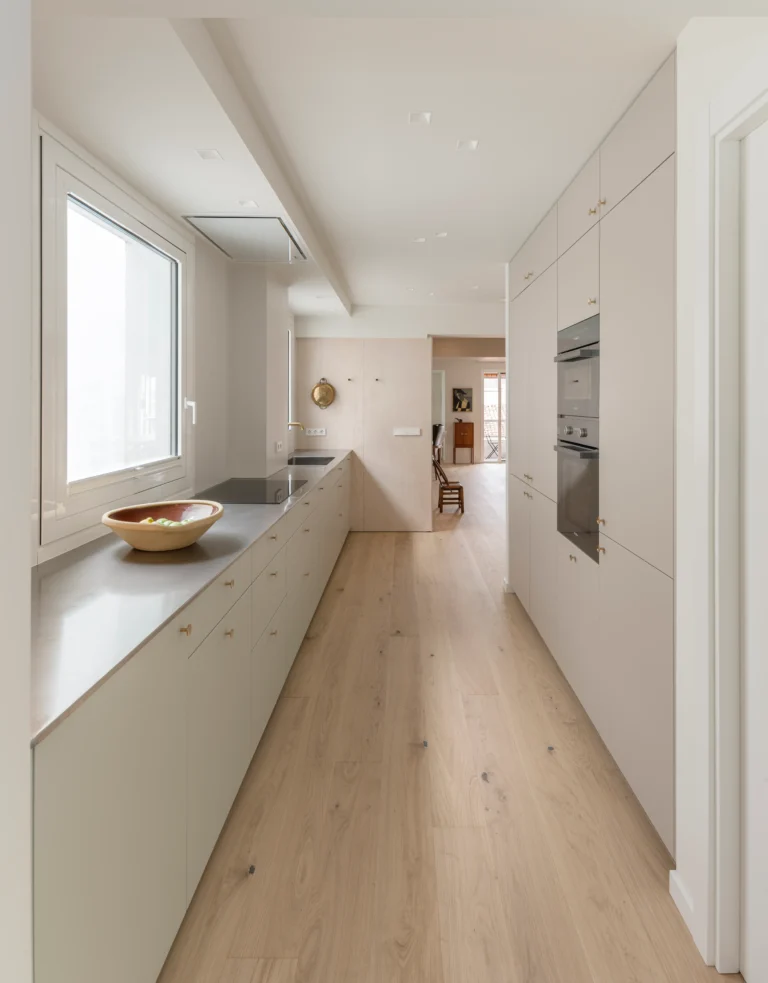 Cocina abierta con muebles bajos en laca menta y encimera de acero en vivienda de Vitoria.